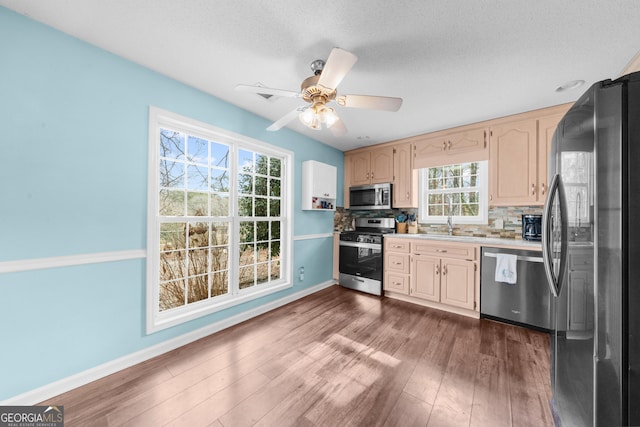 kitchen with light countertops, backsplash, appliances with stainless steel finishes, dark wood-type flooring, and baseboards