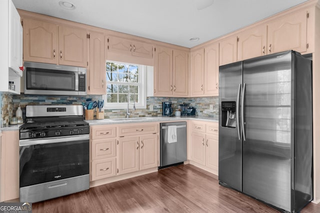 kitchen featuring light countertops, decorative backsplash, appliances with stainless steel finishes, dark wood-type flooring, and a sink