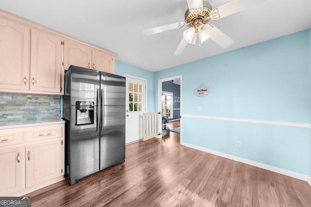 kitchen featuring baseboards, decorative backsplash, stainless steel fridge with ice dispenser, wood finished floors, and light countertops