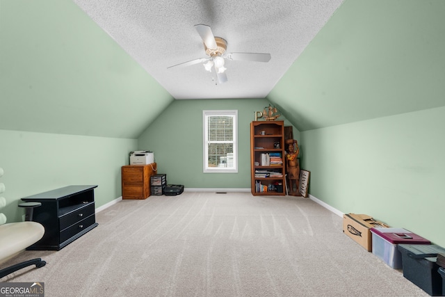 interior space featuring carpet, a ceiling fan, vaulted ceiling, a textured ceiling, and baseboards