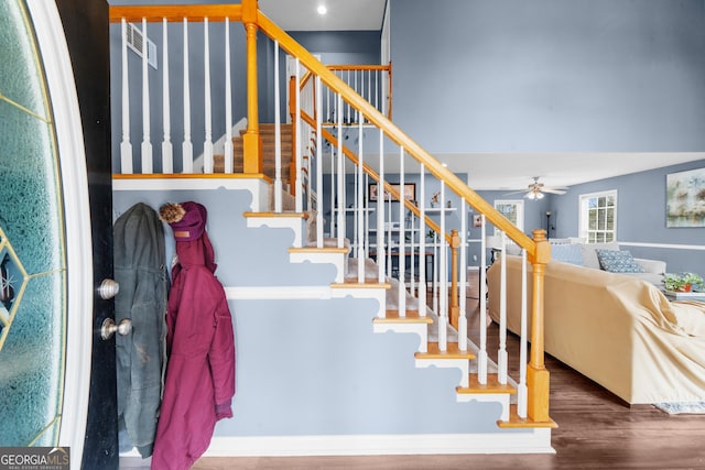 staircase with ceiling fan and wood finished floors