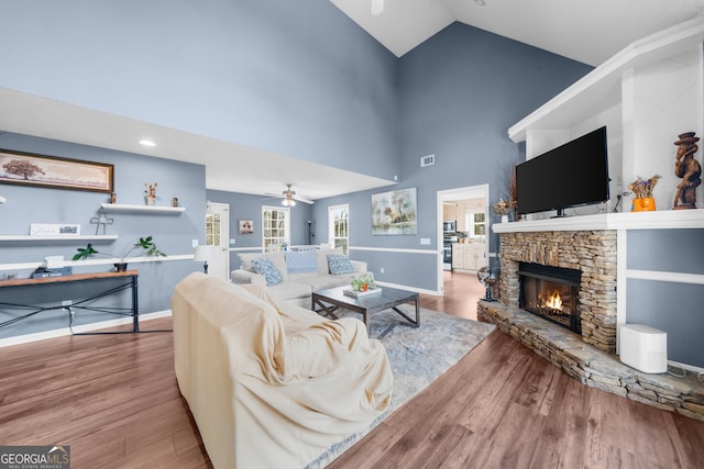 living room with a fireplace, wood finished floors, a ceiling fan, and baseboards