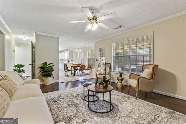 living area with crown molding, visible vents, dark wood-type flooring, a textured ceiling, and baseboards