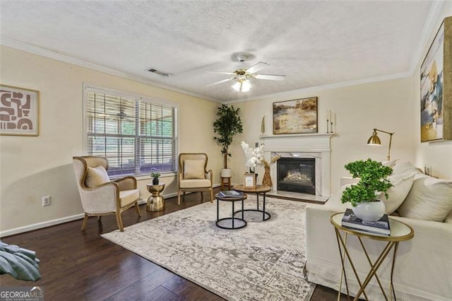 sitting room featuring a textured ceiling, dark wood-type flooring, a fireplace, visible vents, and crown molding