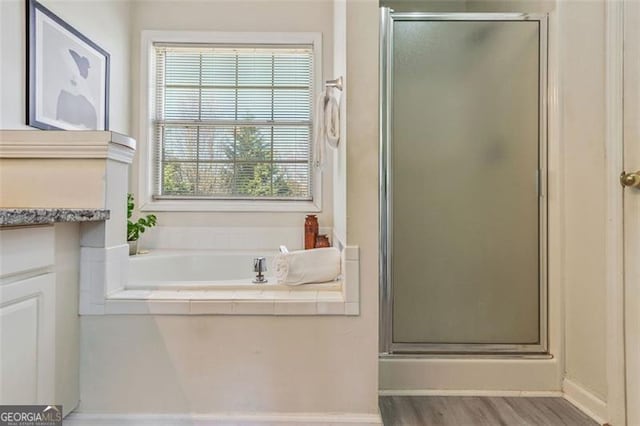 bathroom with vanity, a stall shower, wood finished floors, and a bath