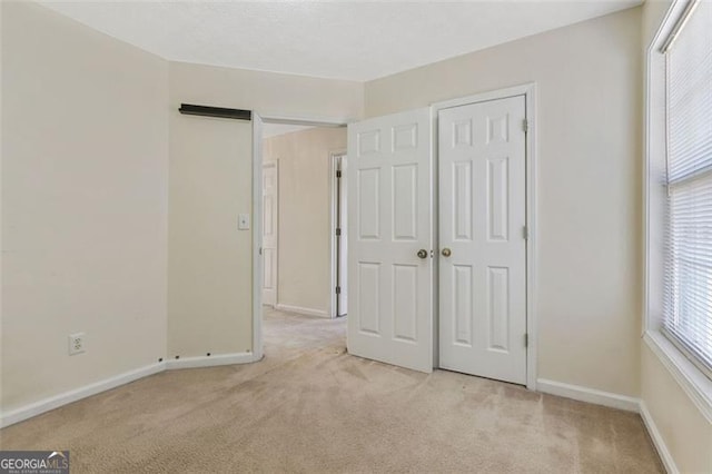 unfurnished bedroom featuring baseboards and light colored carpet