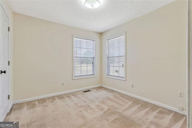 unfurnished bedroom featuring light colored carpet, visible vents, and baseboards