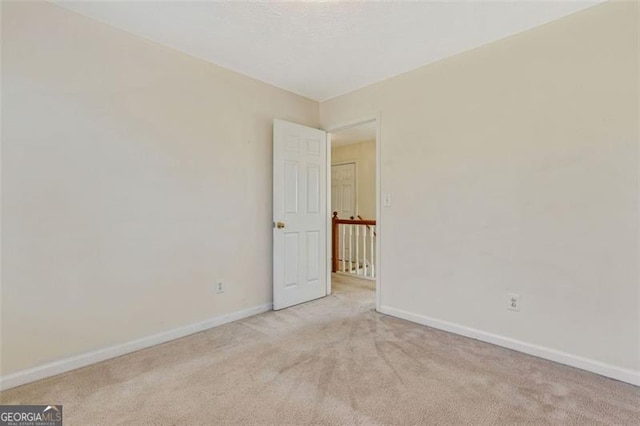 unfurnished room featuring light carpet and baseboards