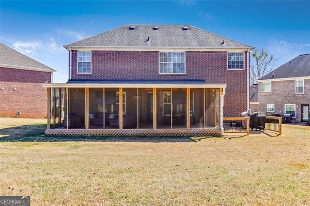 rear view of house featuring a sunroom, roof with shingles, a lawn, and brick siding