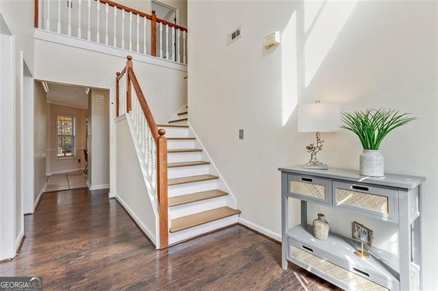 stairway with wood finished floors, visible vents, and baseboards