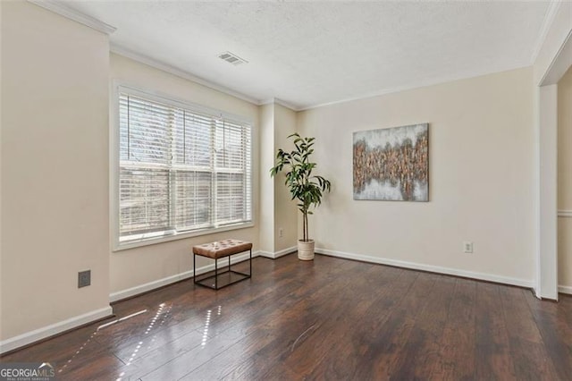 unfurnished room featuring dark wood-style floors, visible vents, crown molding, and baseboards