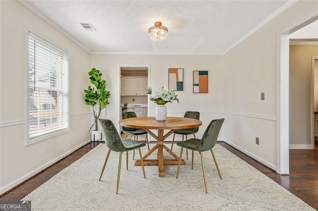 dining room featuring dark wood-style floors, baseboards, visible vents, and crown molding