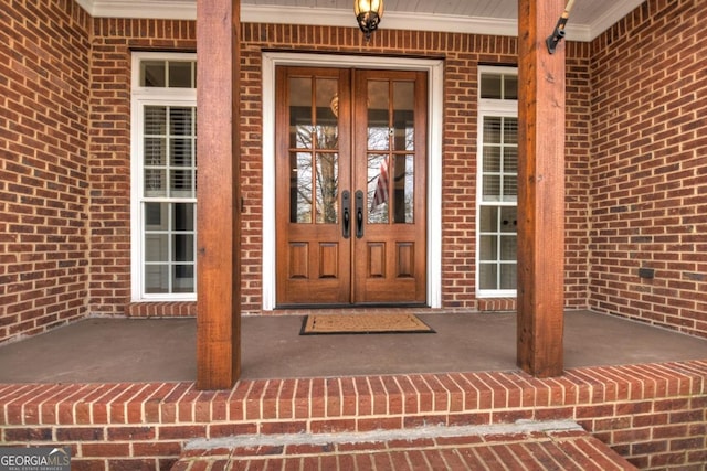 property entrance with brick siding, a porch, and french doors