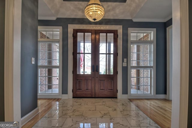 foyer featuring baseboards, marble finish floor, and crown molding