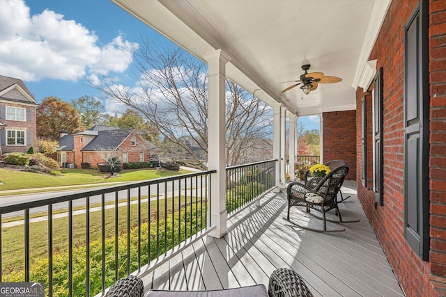 wooden terrace featuring a residential view, a ceiling fan, and a yard