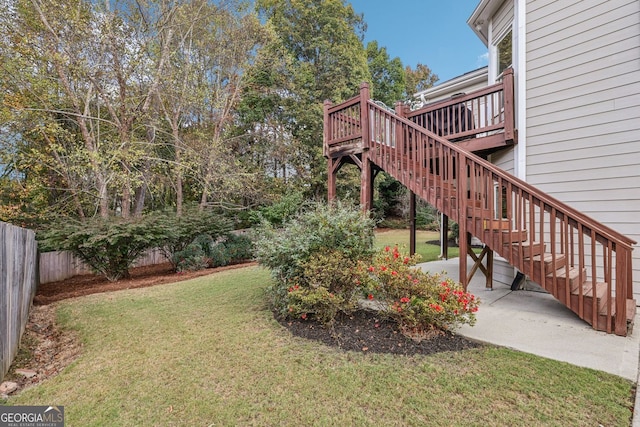 view of yard featuring a patio area, fence, a deck, and stairs