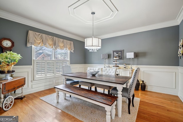 dining area with a wainscoted wall, crown molding, and light wood finished floors