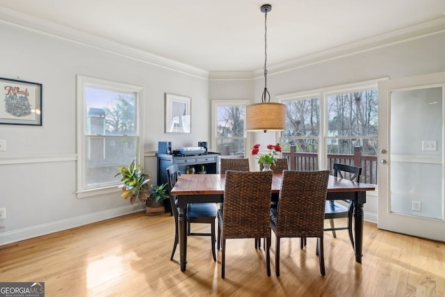 dining room with light wood-style flooring, ornamental molding, and baseboards