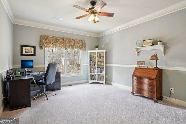 carpeted home office featuring crown molding, a ceiling fan, visible vents, and baseboards