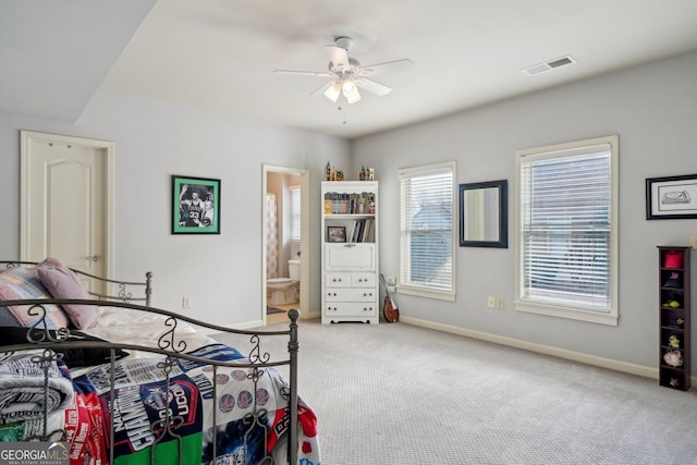 bedroom with carpet floors, a ceiling fan, visible vents, baseboards, and ensuite bath