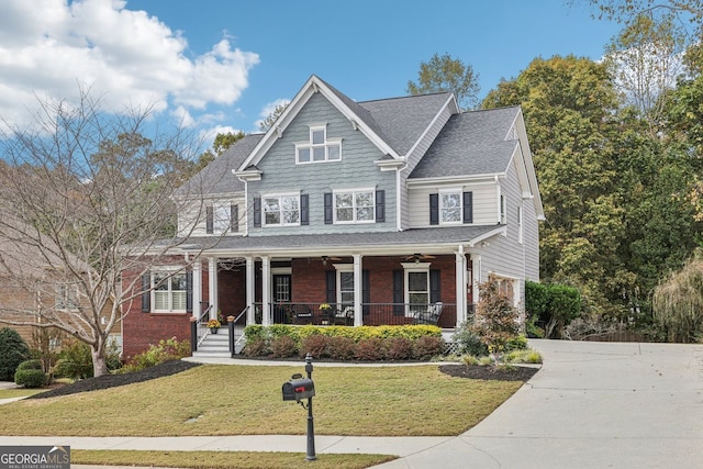 view of front of home with brick siding, concrete driveway, a ceiling fan, covered porch, and a front yard