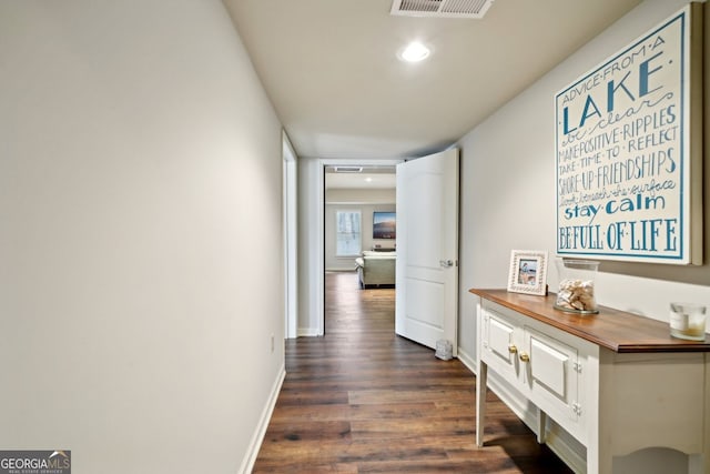 hallway featuring visible vents, dark wood finished floors, and baseboards