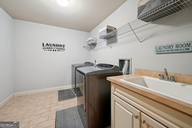 washroom featuring independent washer and dryer, a sink, cabinet space, and baseboards