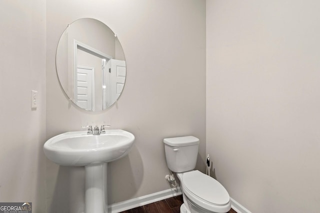 bathroom featuring baseboards, a sink, toilet, and wood finished floors