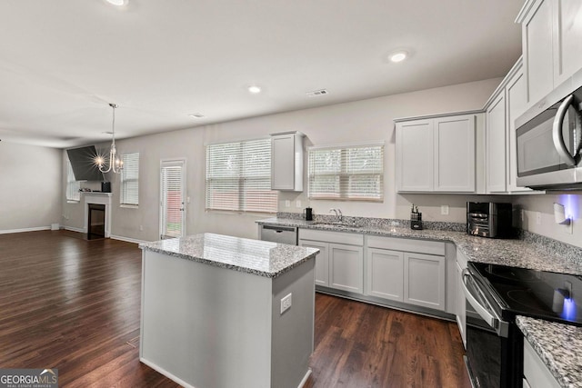 kitchen with dark wood-style flooring, white cabinetry, appliances with stainless steel finishes, a center island, and pendant lighting