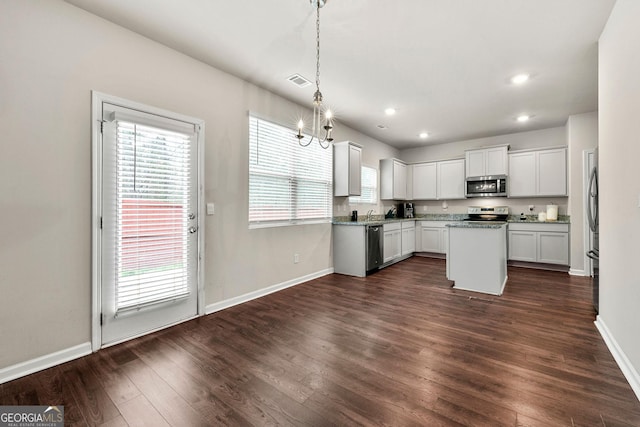 kitchen featuring appliances with stainless steel finishes, a center island, white cabinets, and decorative light fixtures