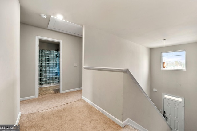 hall featuring baseboards, light carpet, and an upstairs landing