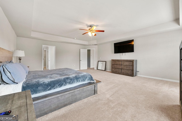 bedroom with a ceiling fan, a tray ceiling, carpet flooring, and baseboards