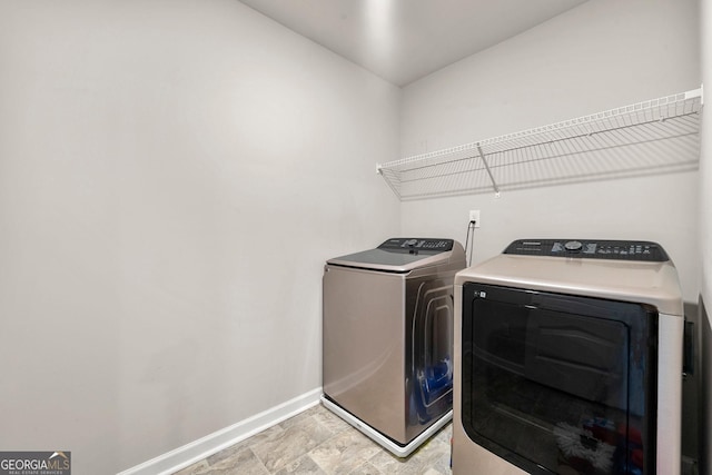 clothes washing area with laundry area, washer and clothes dryer, and baseboards