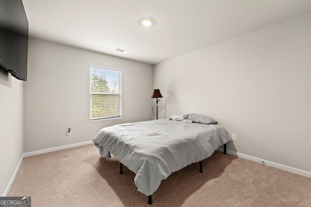 bedroom with baseboards, visible vents, and light colored carpet