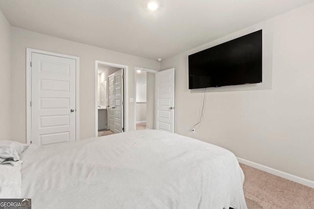 bedroom with ensuite bathroom, carpet flooring, and baseboards