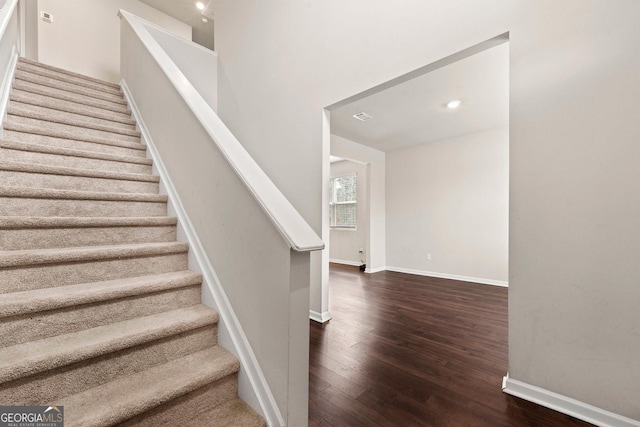 stairs featuring wood finished floors, visible vents, and baseboards