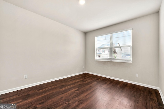 unfurnished room featuring dark wood-type flooring and baseboards