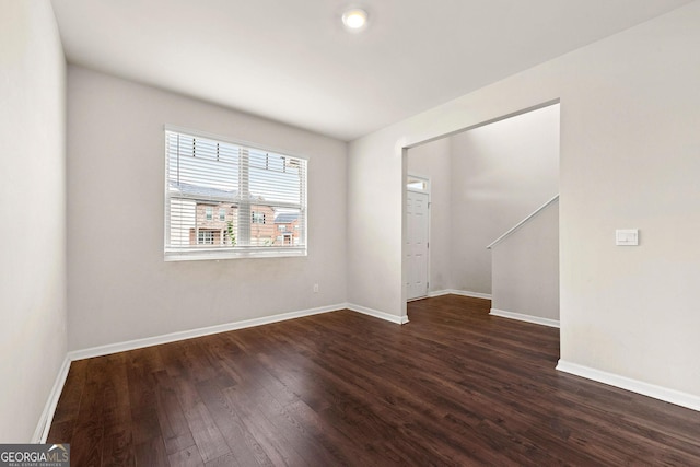 unfurnished room featuring dark wood-style flooring and baseboards