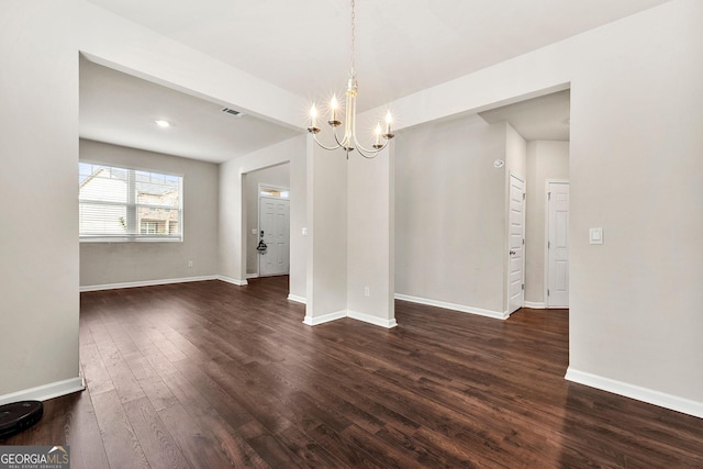 unfurnished dining area featuring dark wood-style flooring, an inviting chandelier, and baseboards