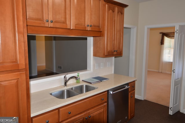 kitchen with brown cabinets, light countertops, dark colored carpet, stainless steel dishwasher, and a sink