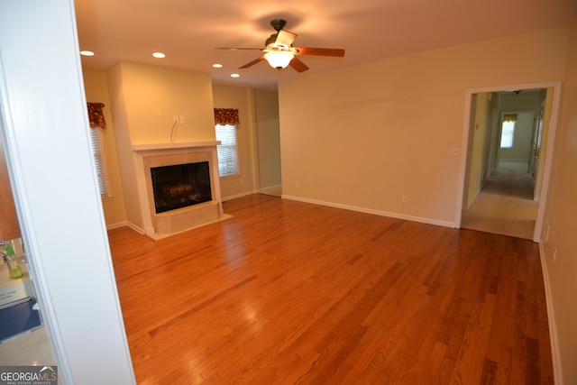 unfurnished living room with a fireplace with flush hearth, plenty of natural light, wood finished floors, and recessed lighting