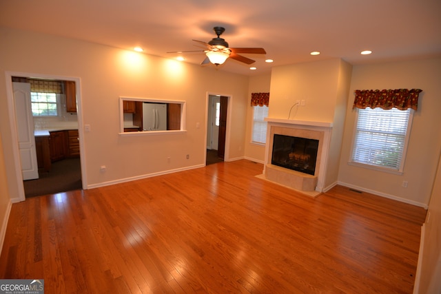 unfurnished living room with recessed lighting, wood finished floors, visible vents, baseboards, and a tiled fireplace