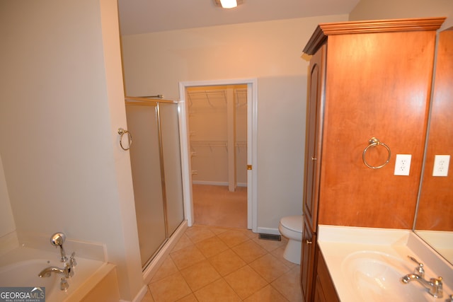 full bath featuring a walk in closet, a garden tub, a stall shower, vanity, and tile patterned floors