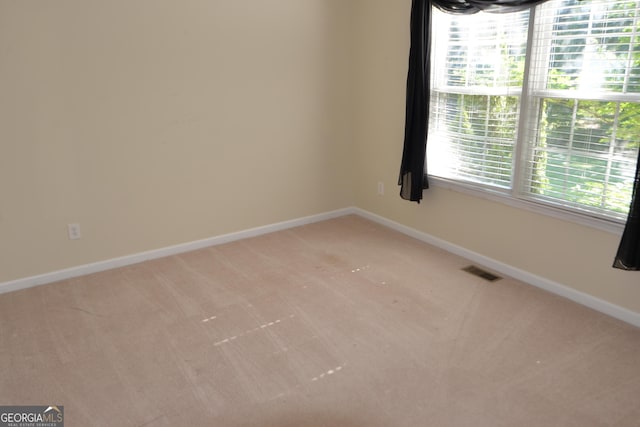 carpeted spare room featuring baseboards and visible vents