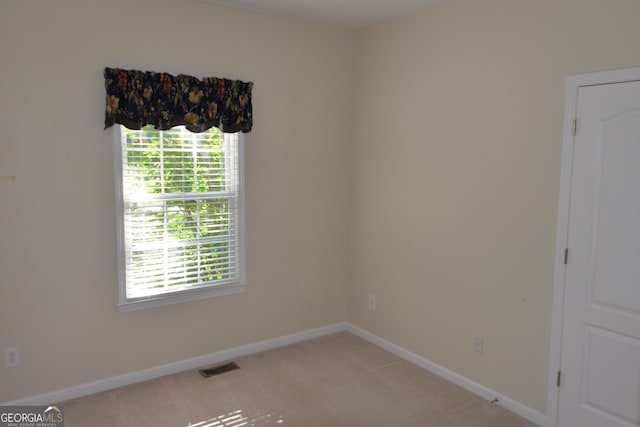 carpeted empty room featuring baseboards and visible vents