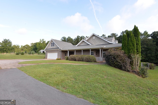 craftsman-style house with aphalt driveway, a porch, an attached garage, brick siding, and a front yard