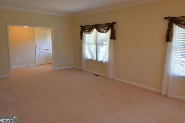 spare room featuring light colored carpet, crown molding, visible vents, and baseboards