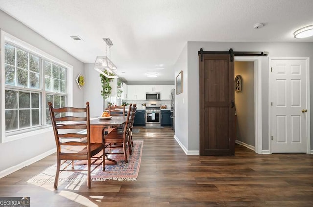 dining room with a barn door, visible vents, baseboards, and dark wood-type flooring