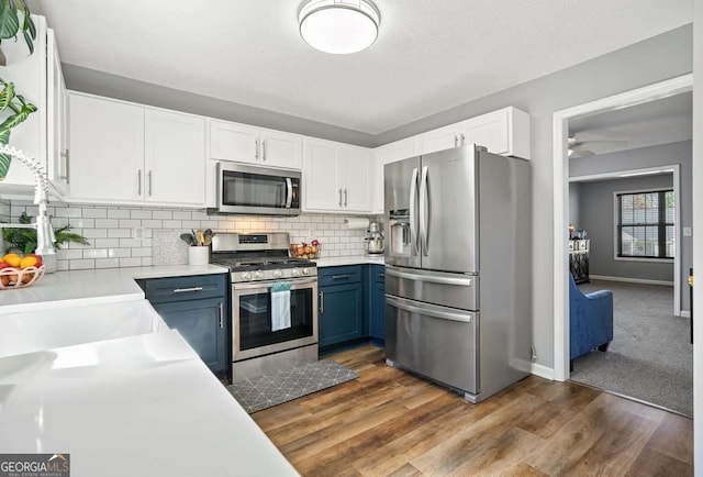 kitchen featuring blue cabinetry, stainless steel appliances, tasteful backsplash, light countertops, and white cabinets