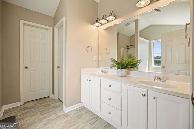 full bathroom featuring lofted ceiling, double vanity, a sink, and wood finished floors